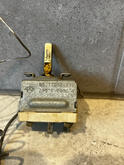 Close-up view of a temperature control thermostat switch with a metal lever and marked 290°C on metal casing