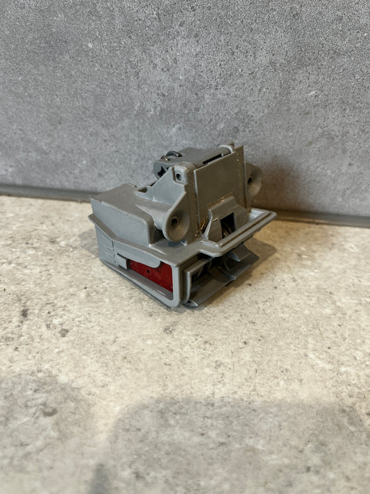 Gray plastic electrical terminal block with red indicator on cement background