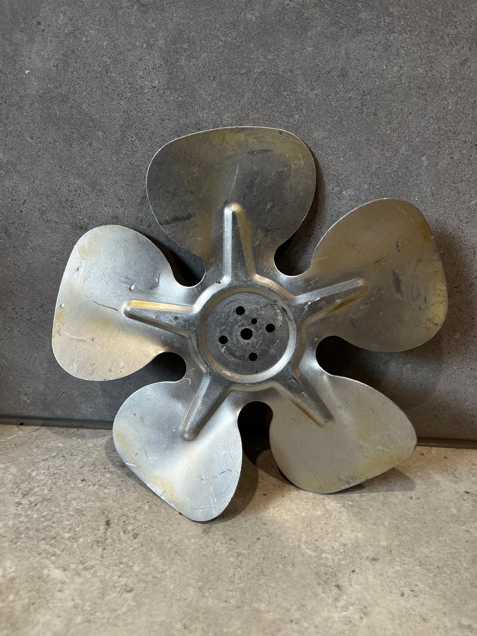 Metal five-blade fan replacement part on gray background