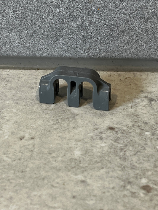 Gray plastic pipe support bracket on concrete surface