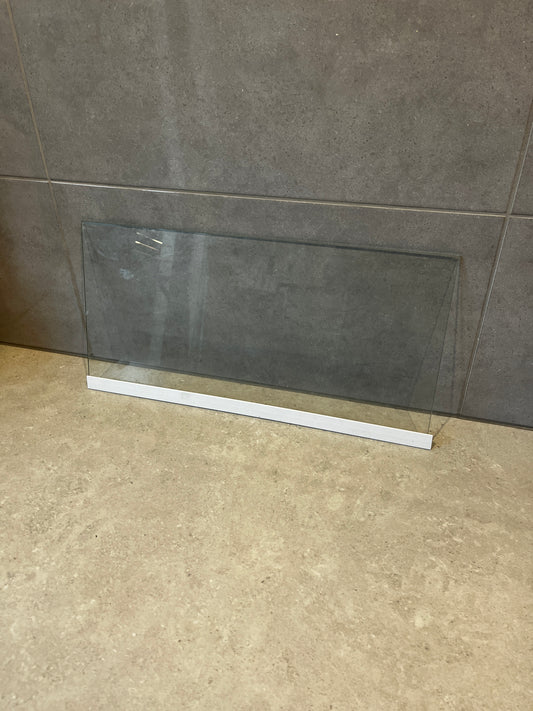 Clear safety glass panel with white base resting on stone surface