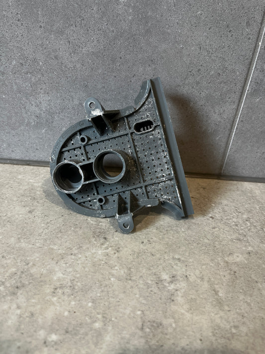 Gray plastic washer pump housing part standing upright on a tile surface