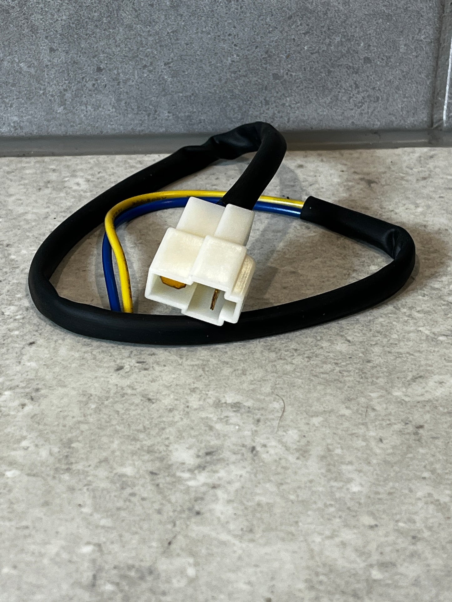 Wiring harness with white two-pin connector and color-coded wires on a gray surface