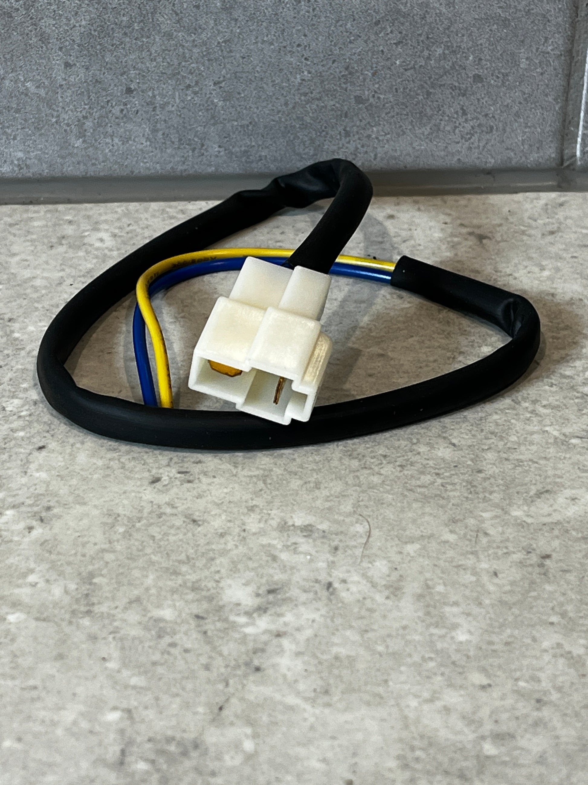 Wiring harness with white two-pin connector and color-coded wires on a gray surface