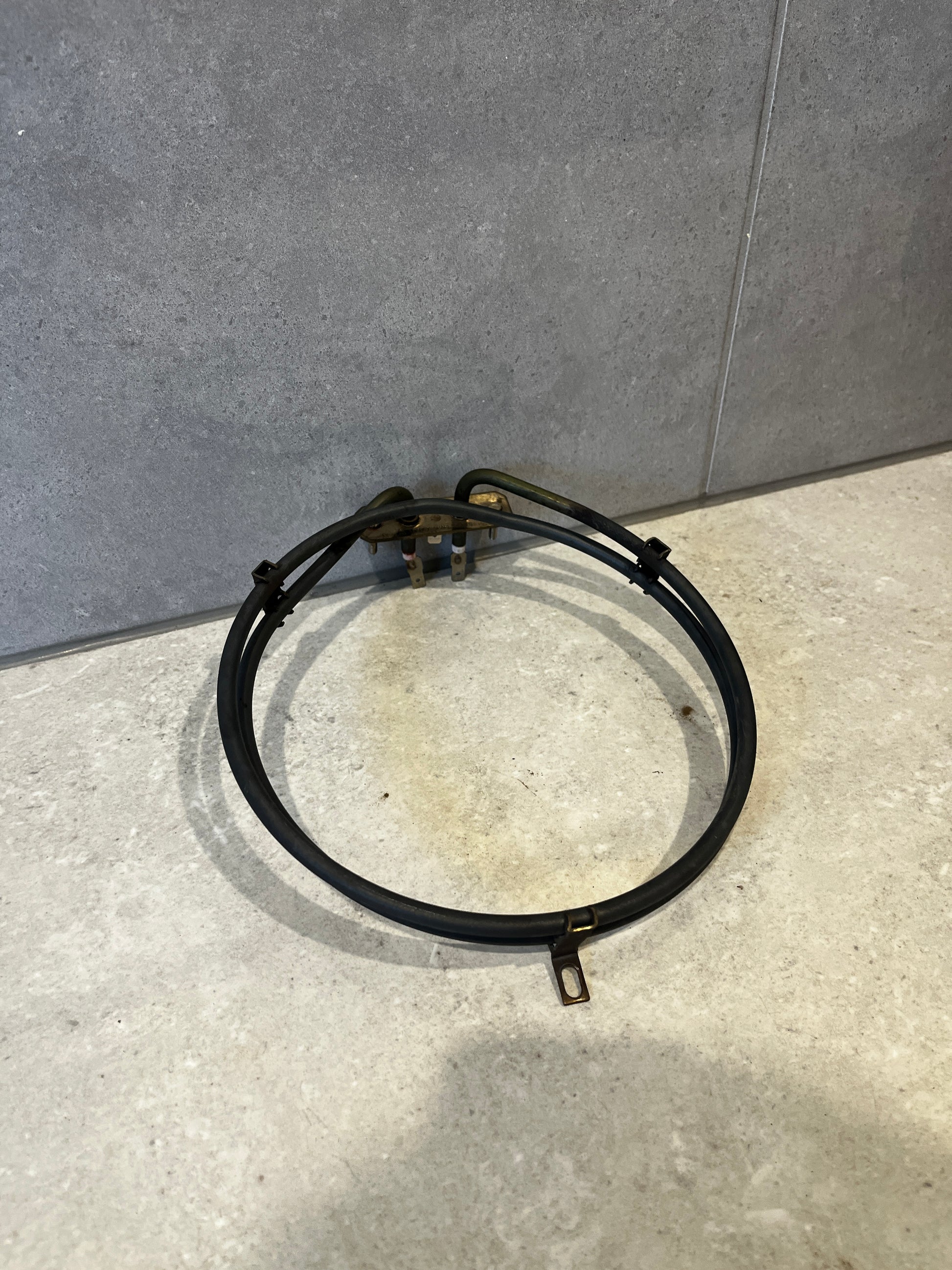 Electric oven heating element coiled and placed on light grey tile surface