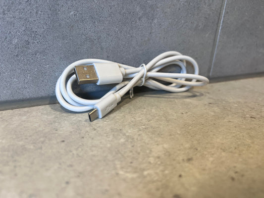 White USB-A to USB-C charging cable coiled on a gray surface