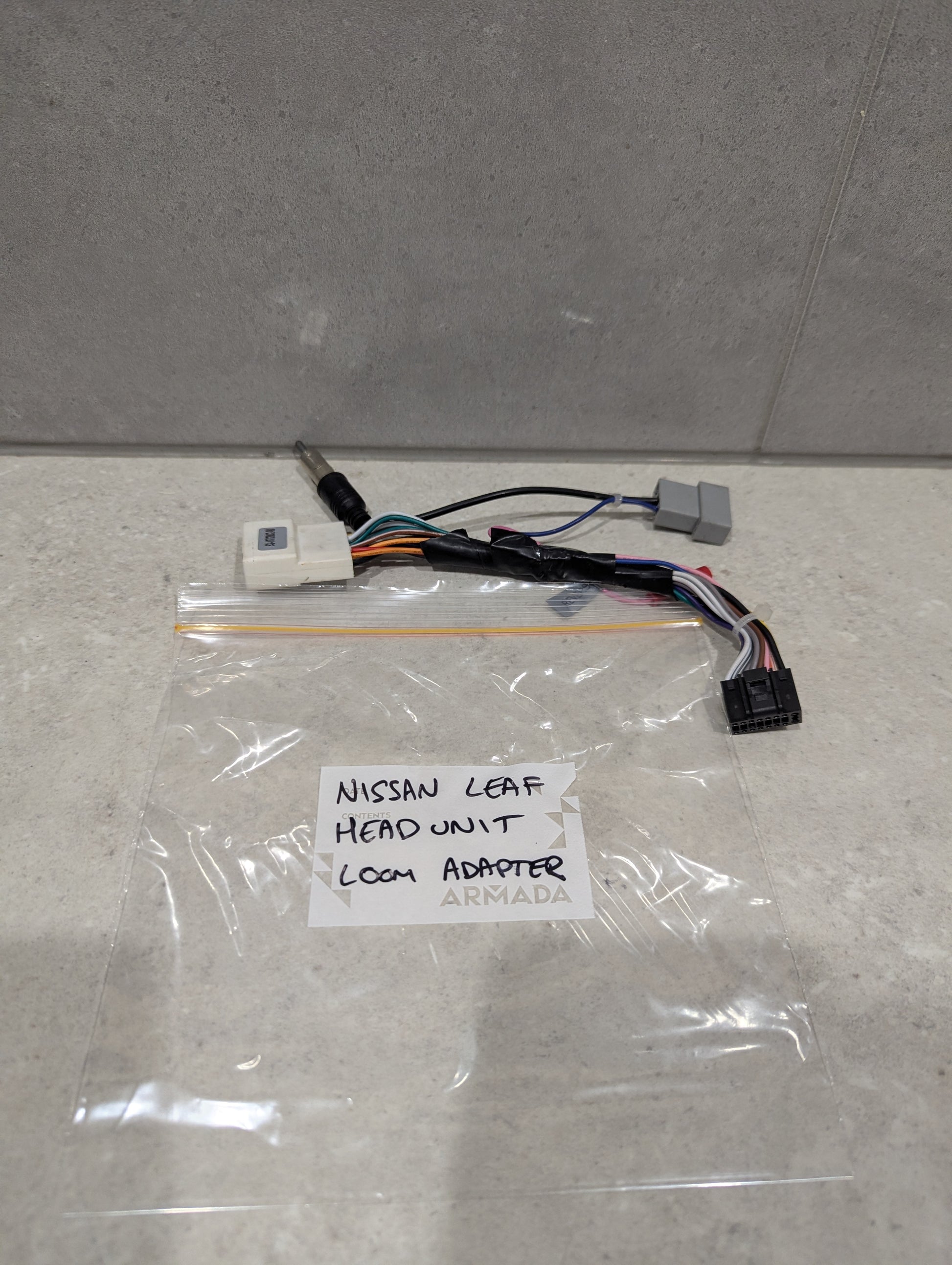 Nissan Leaf head unit loom adapter wiring harness on a countertop with labeled bag