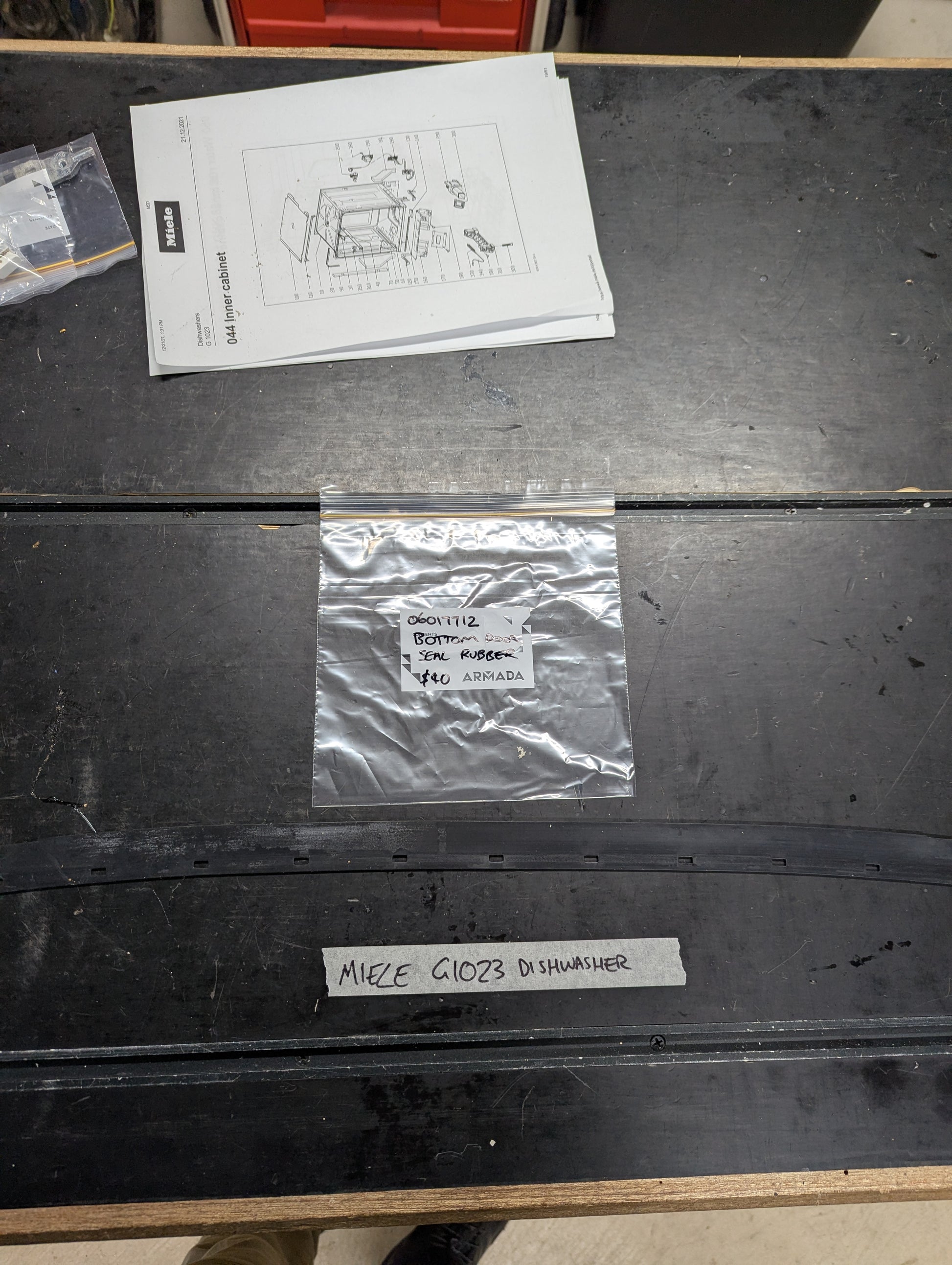 Miele G1023 dishwasher bottom door seal with labeled packaging on workbench
