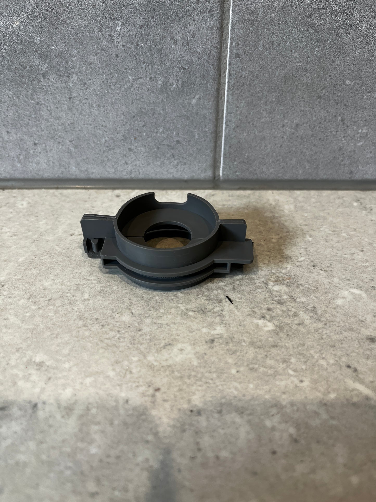 Front view of a durable gray plastic connector fitting on a tile surface