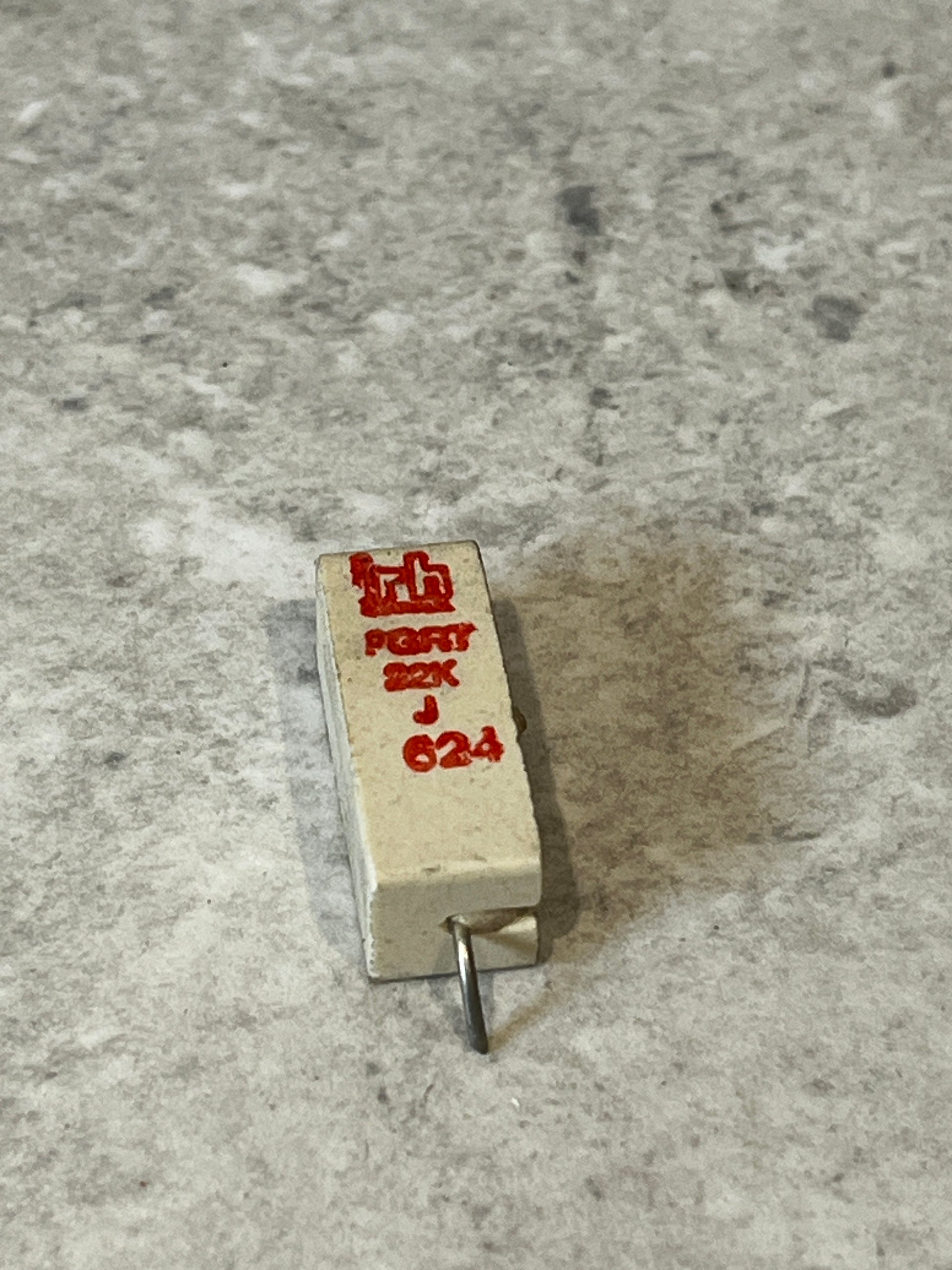 22K ohm ceramic power resistor with visible lead on gray surface
