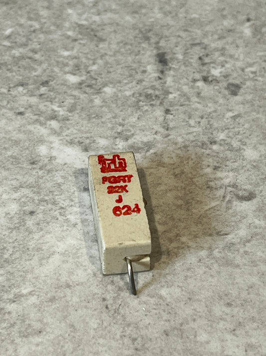 22K ohm ceramic power resistor with visible lead on gray surface