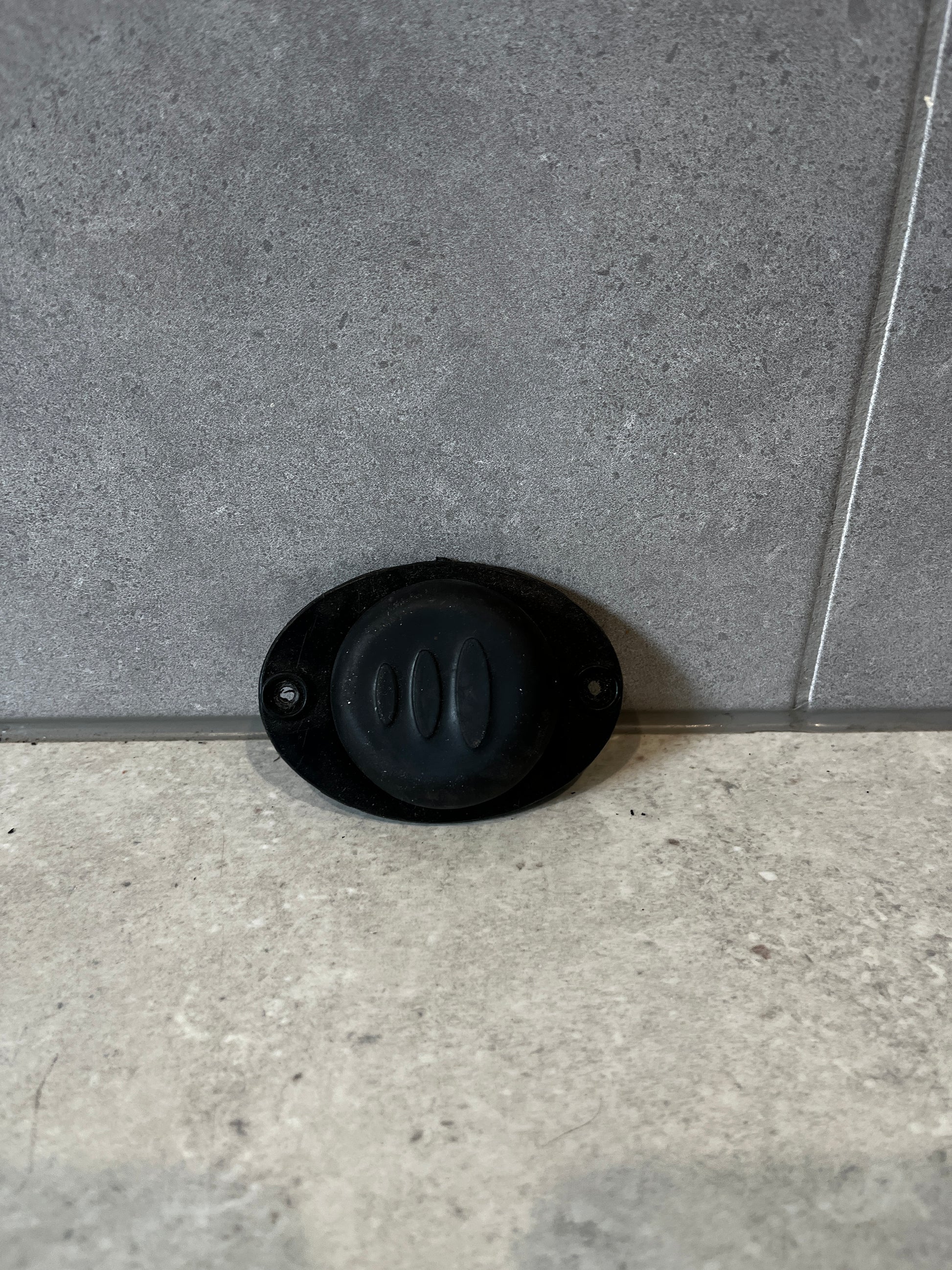 Black rubber door stop mounted on wall with screws