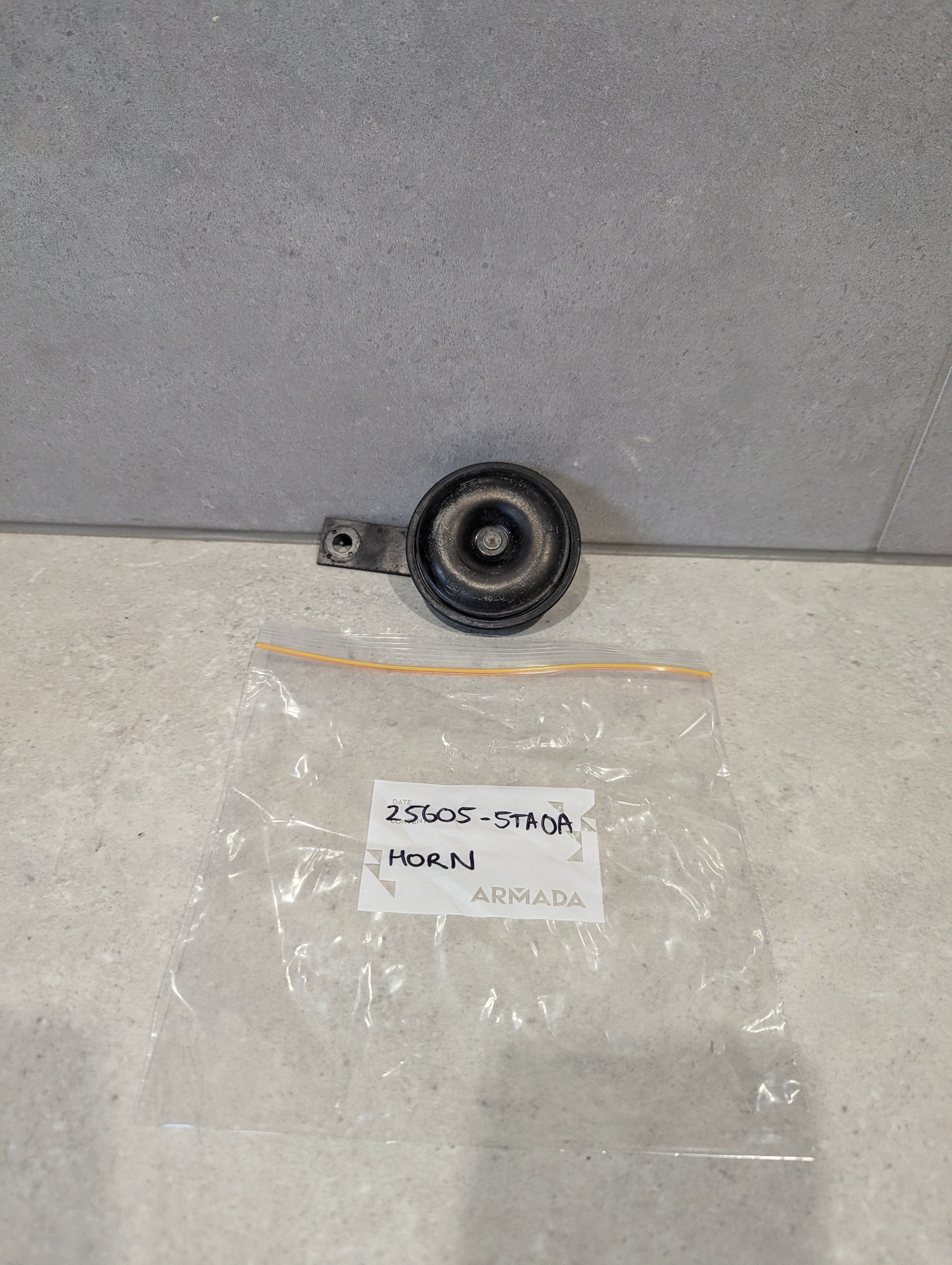 Black round vehicle horn unit with labeled ARMADA bag