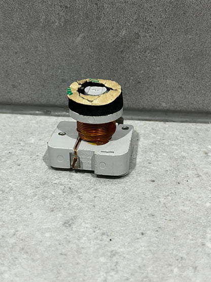 Copper coil component mounted on white plastic base viewed from front