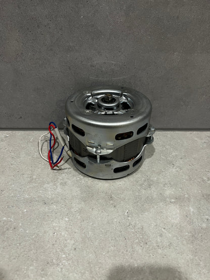 Compact electric motor with metal casing and color-coded wiring on a stone surface