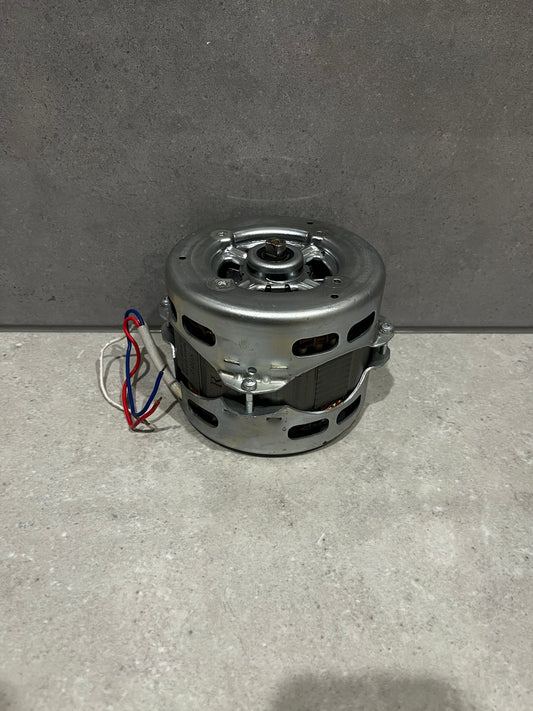 Compact electric motor with metal casing and color-coded wiring on a stone surface