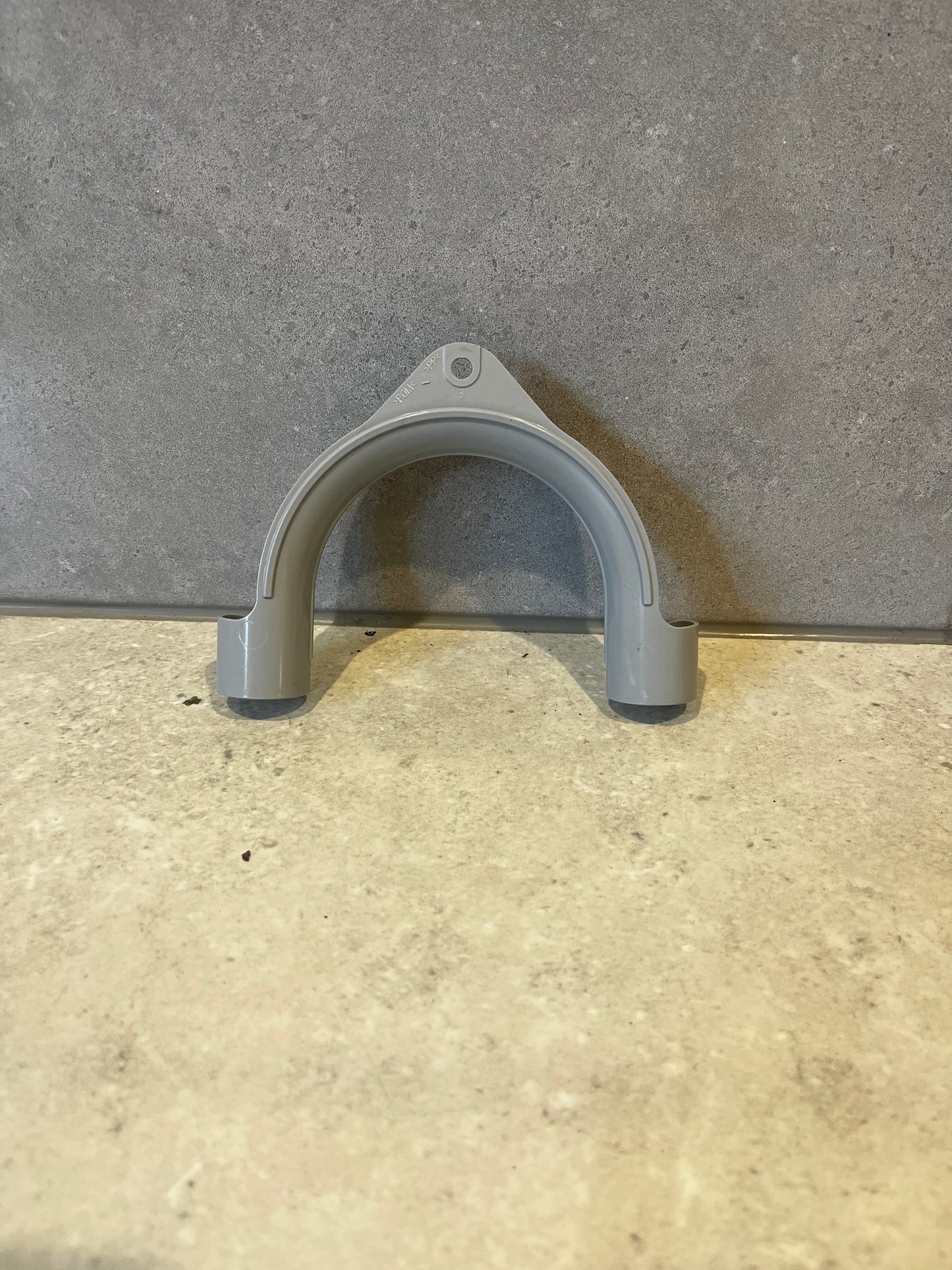 Gray plastic pipe hanger on stone surface