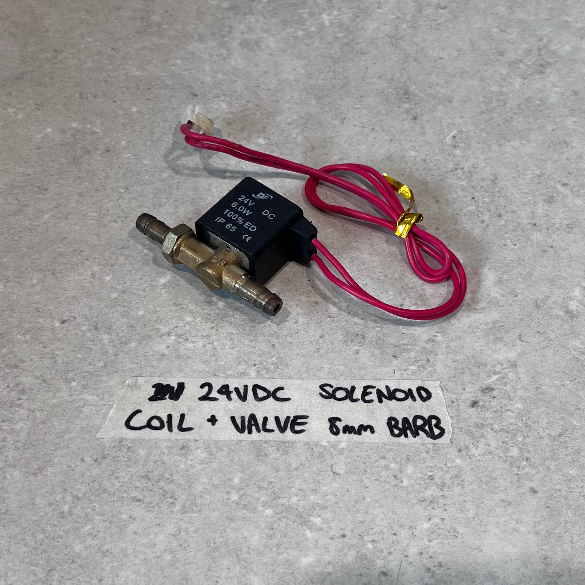 24V DC solenoid coil and valve with 8mm barb fittings and red wires on a gray surface
