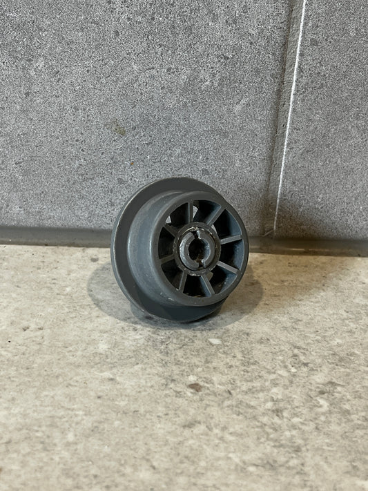 Gray plastic dishwasher lower rack wheel viewed from the side showing the wheel and central hole