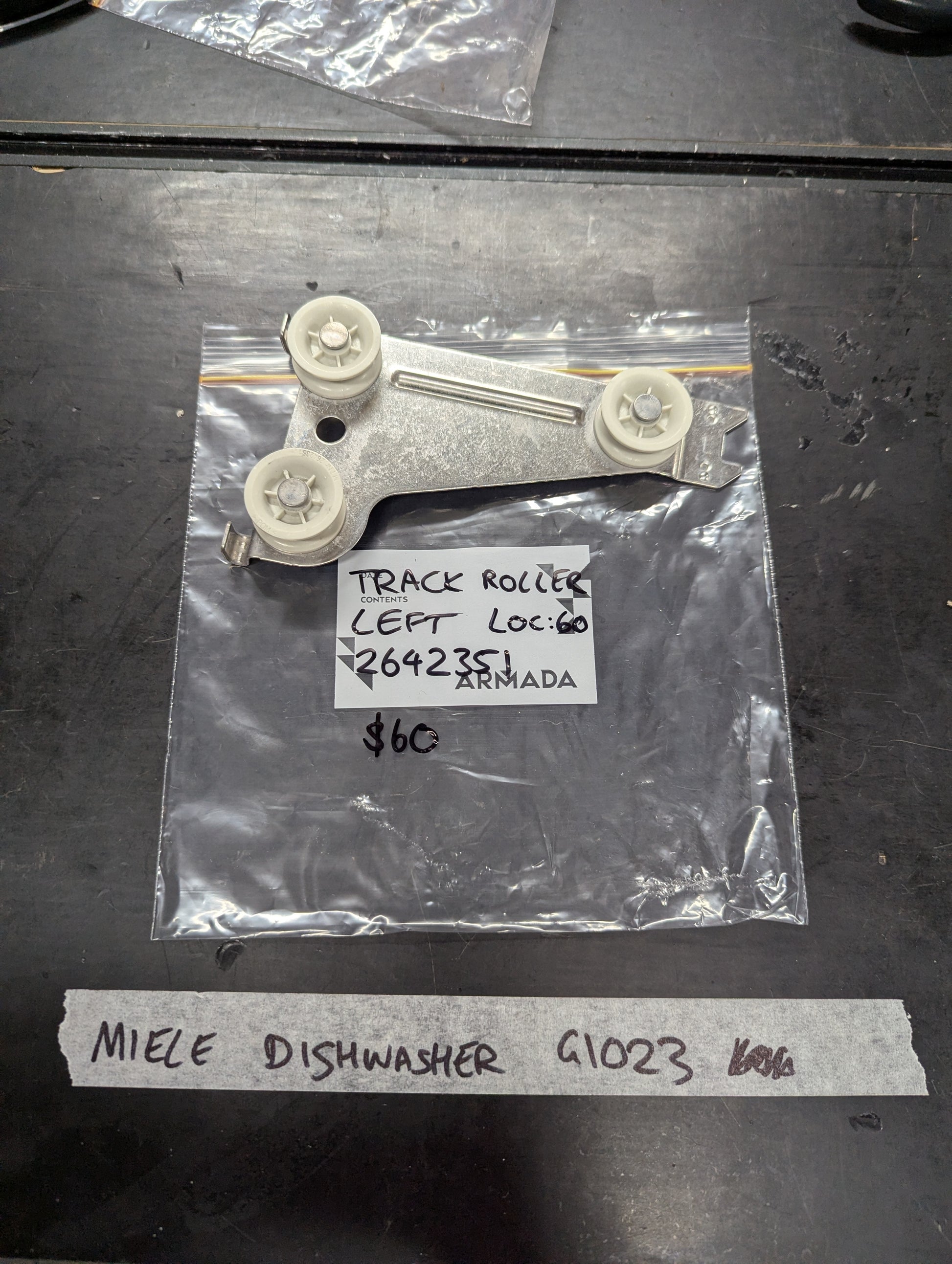 Miele G1023 dishwasher left track roller assembly on black surface