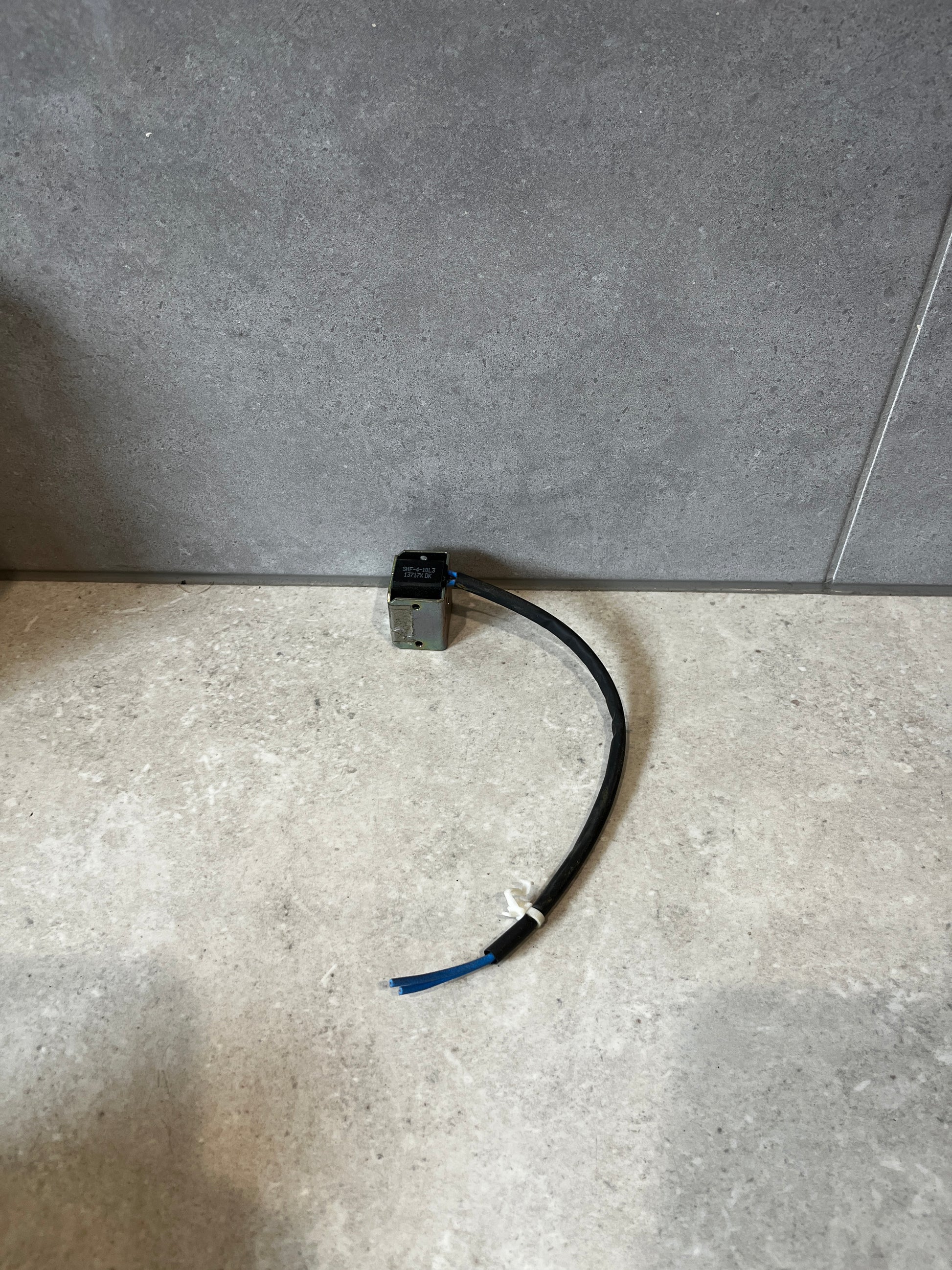 Electromagnetic solenoid coil with attached cable on stone surface