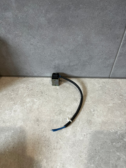 Electromagnetic solenoid coil with attached cable on stone surface