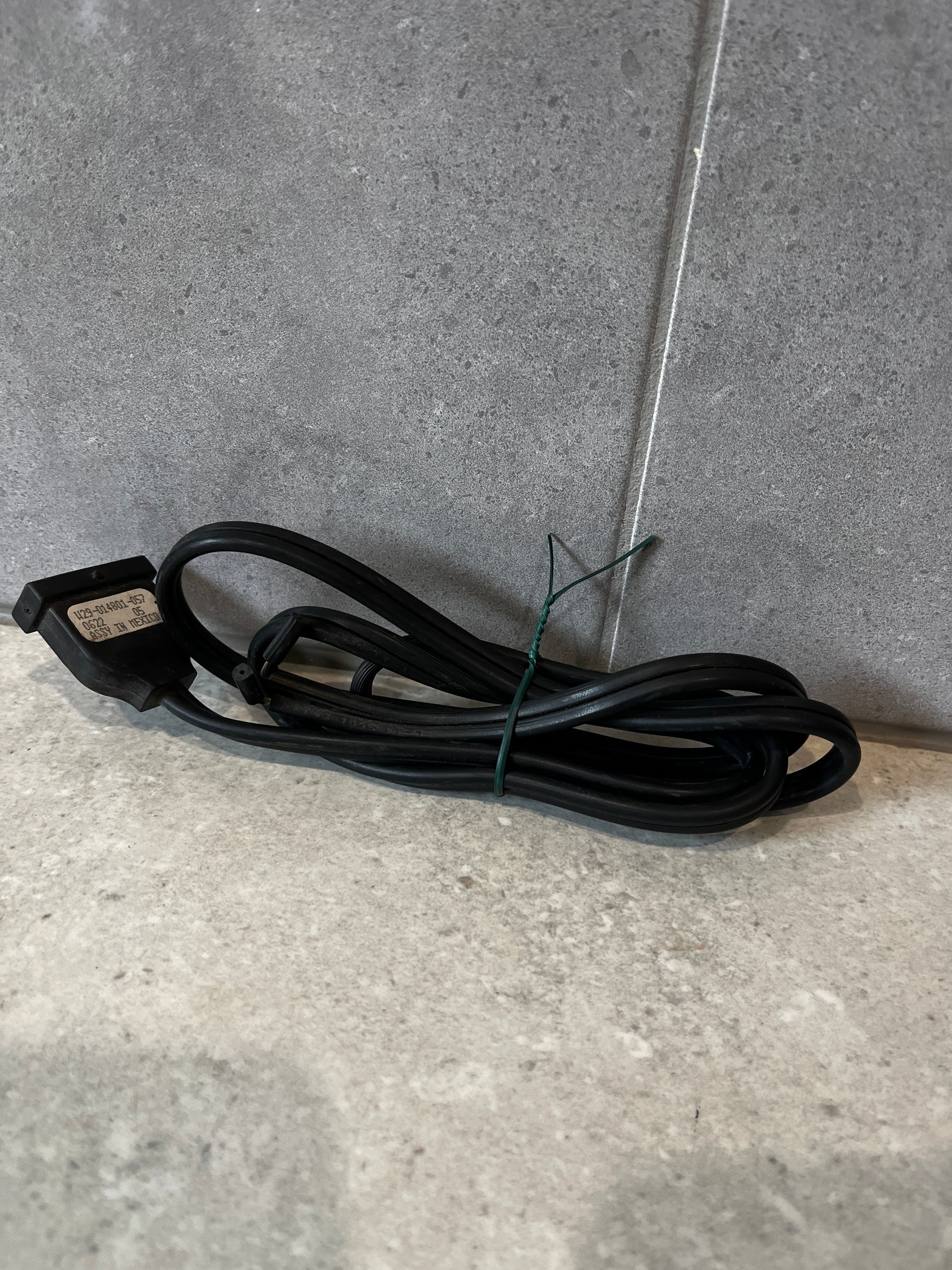 Coiled two-prong black power cord on a stone surface