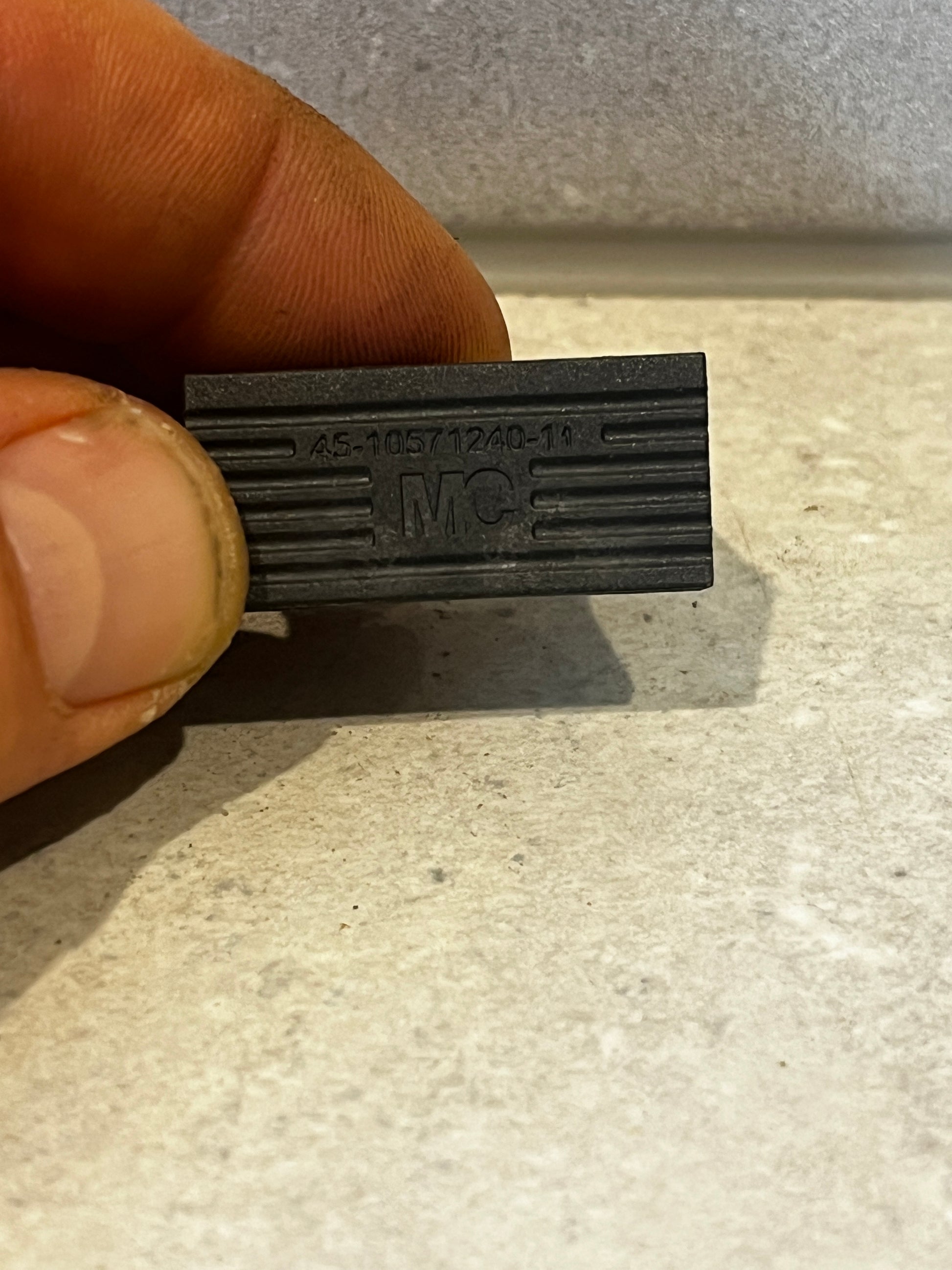 Close-up of black plastic U-shaped spacer block with code and MC logo