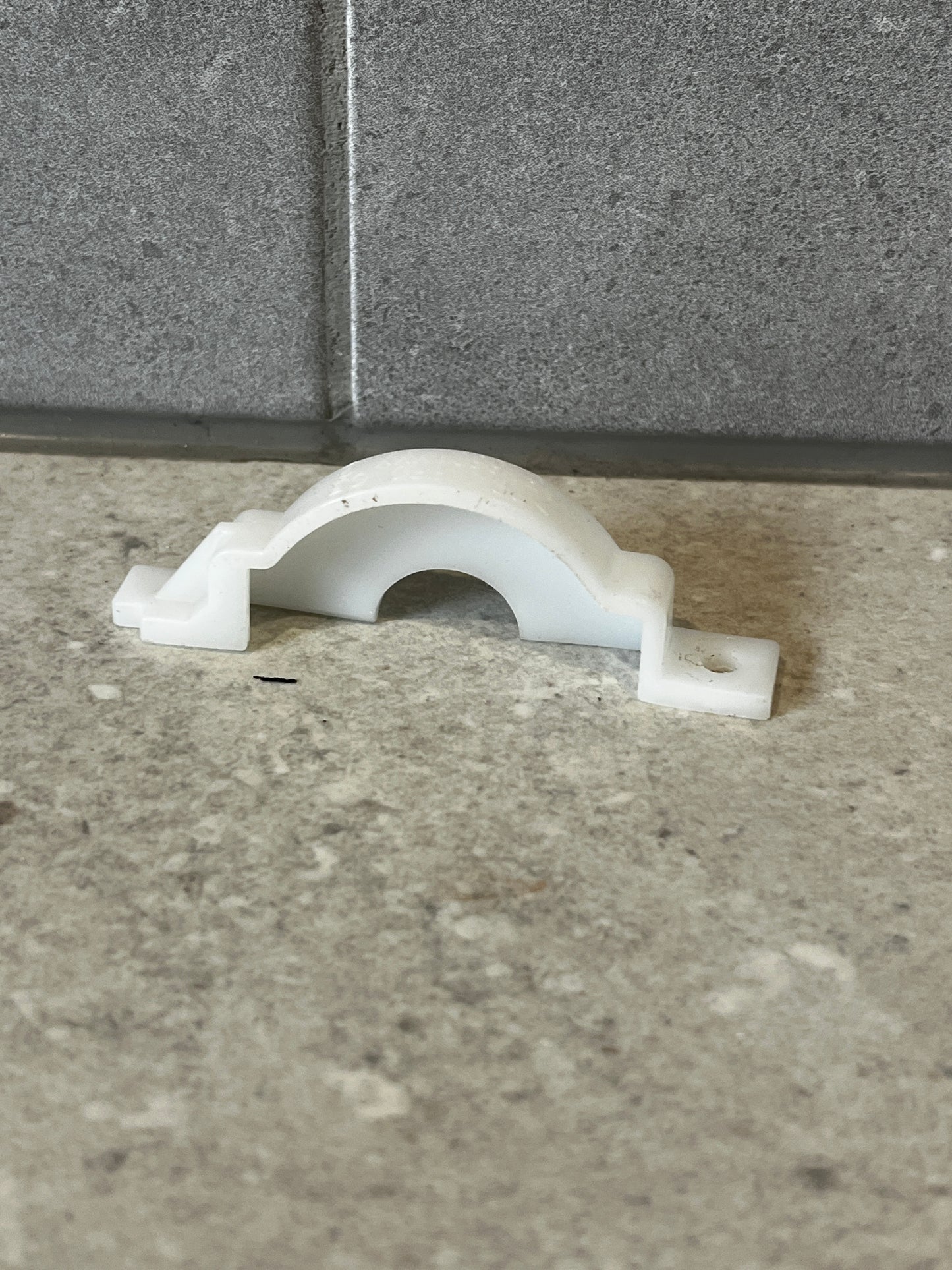 White polypropylene pipe support clamp on stone surface