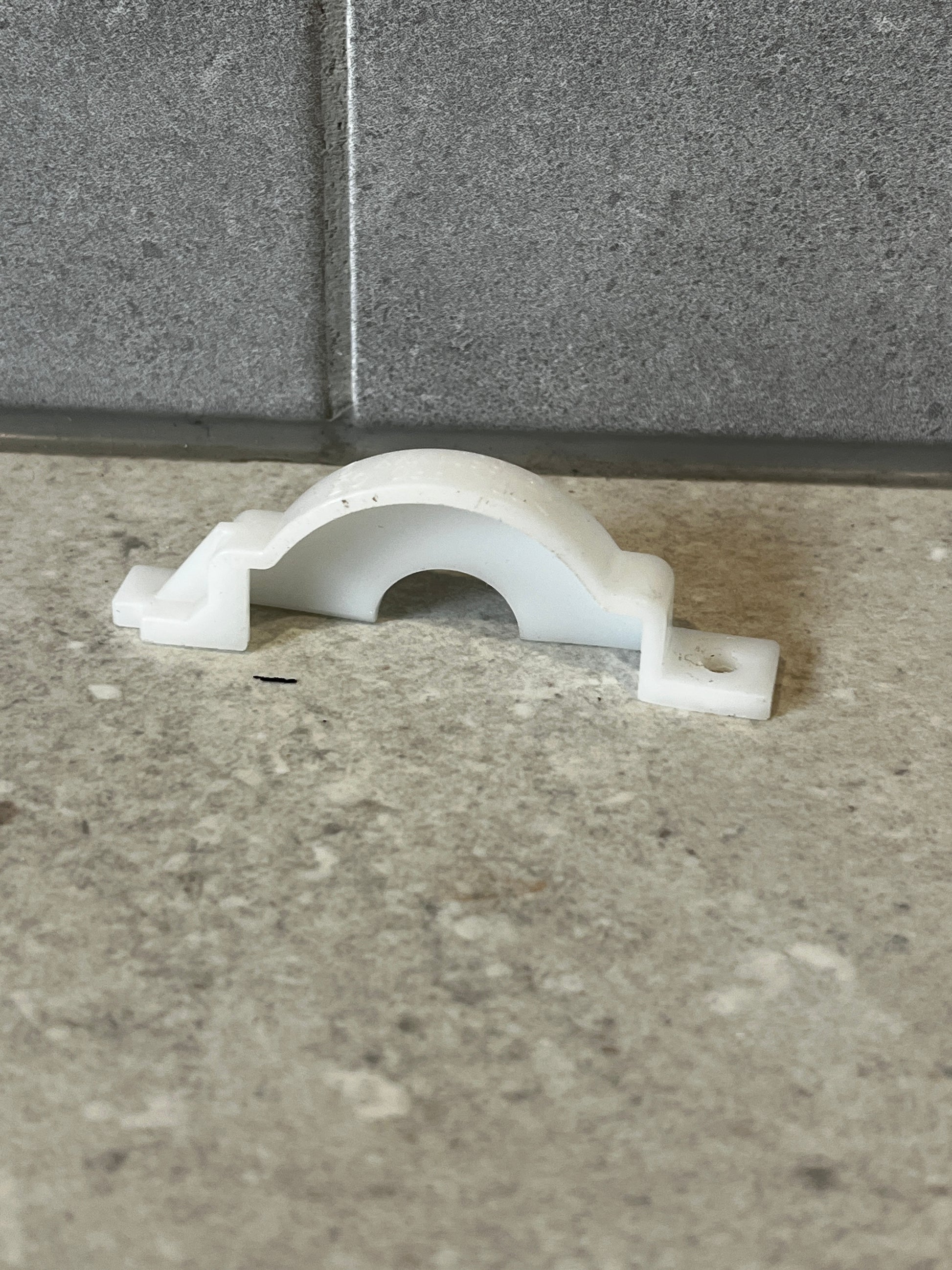 White polypropylene pipe support clamp on stone surface