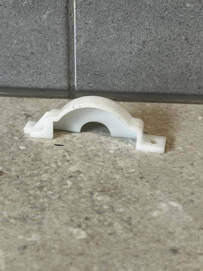 White polypropylene pipe support clamp on stone surface