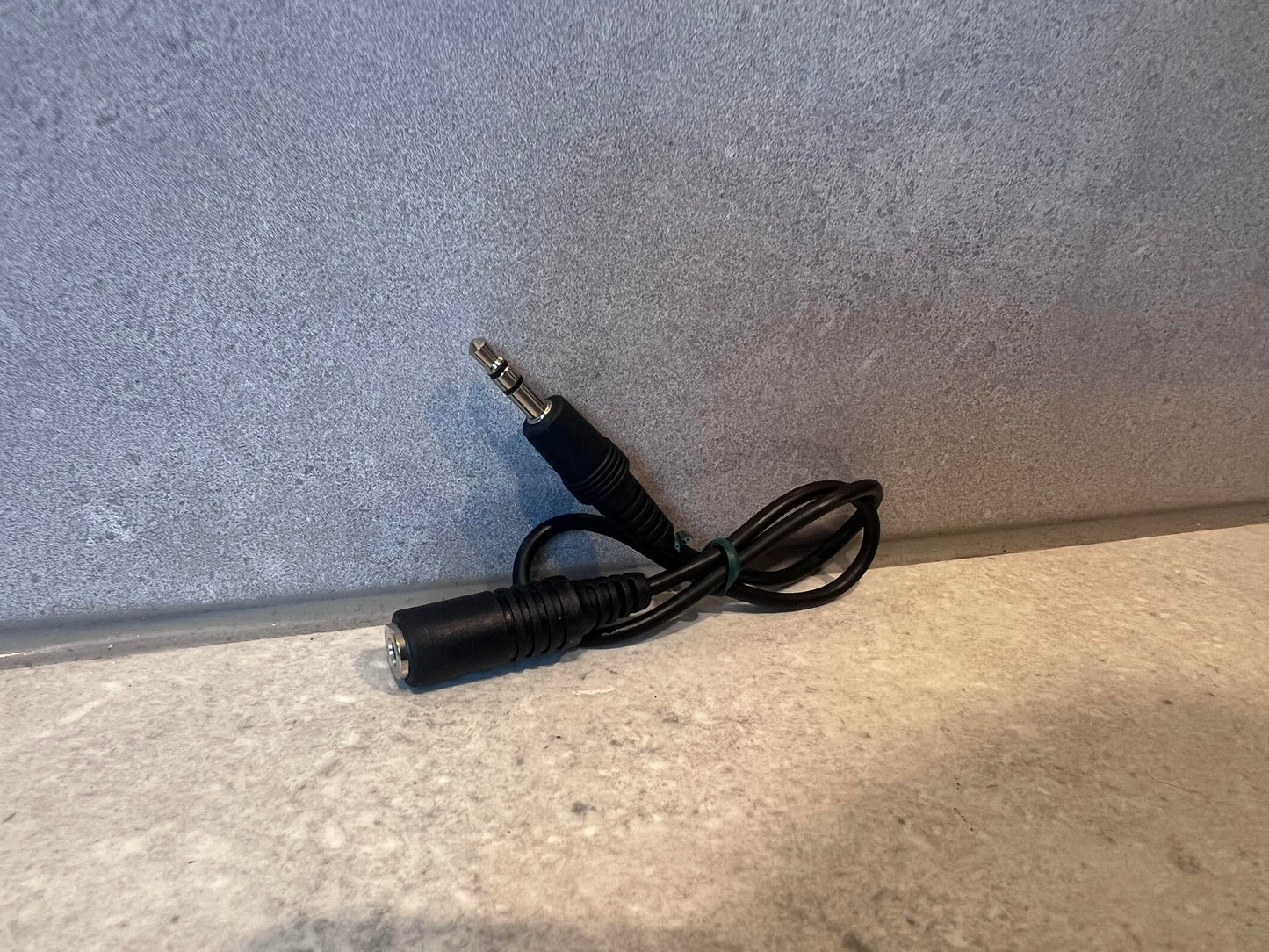 Black 3.5mm male-to-female audio extension cable on a gray surface