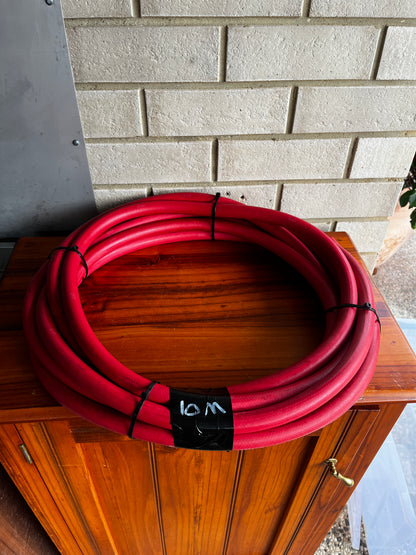 Coiled red Continental ContiTech ORTAC industrial hose on wooden cabinet
