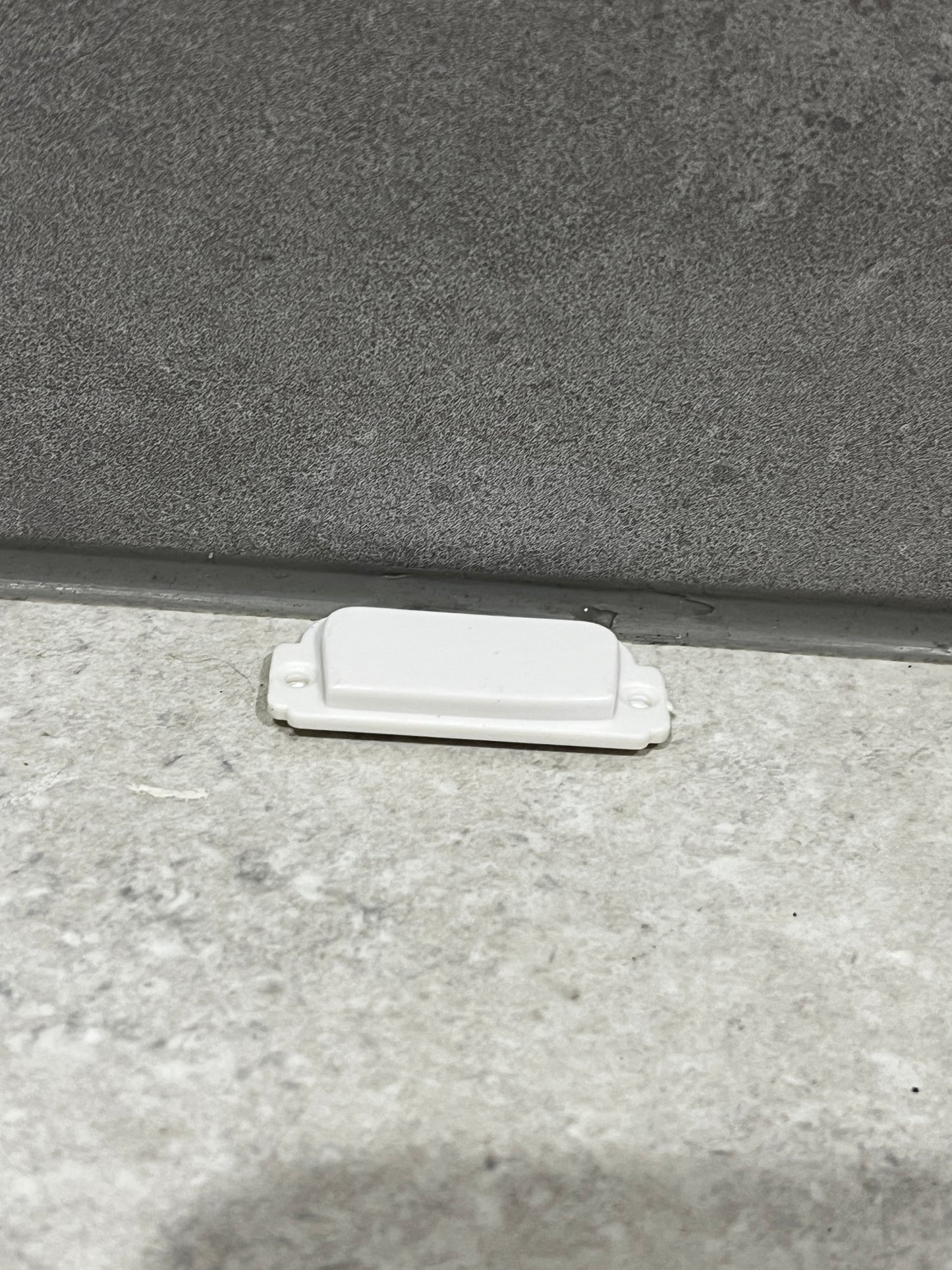 White plastic door stopper fixed at the bottom of a door frame