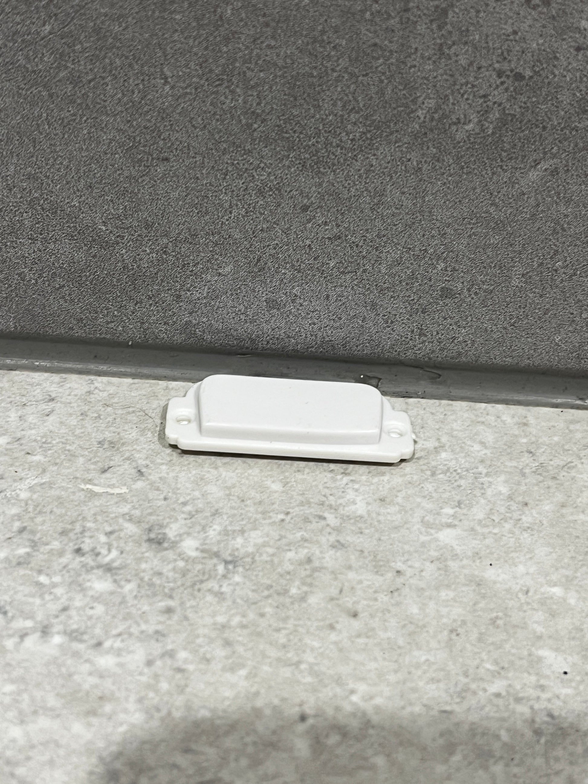 White plastic door stopper fixed at the bottom of a door frame