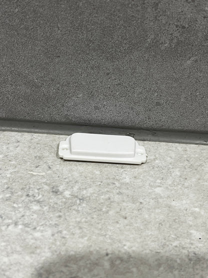 White plastic door stopper fixed at the bottom of a door frame