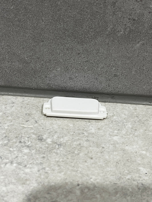 White plastic door stopper fixed at the bottom of a door frame