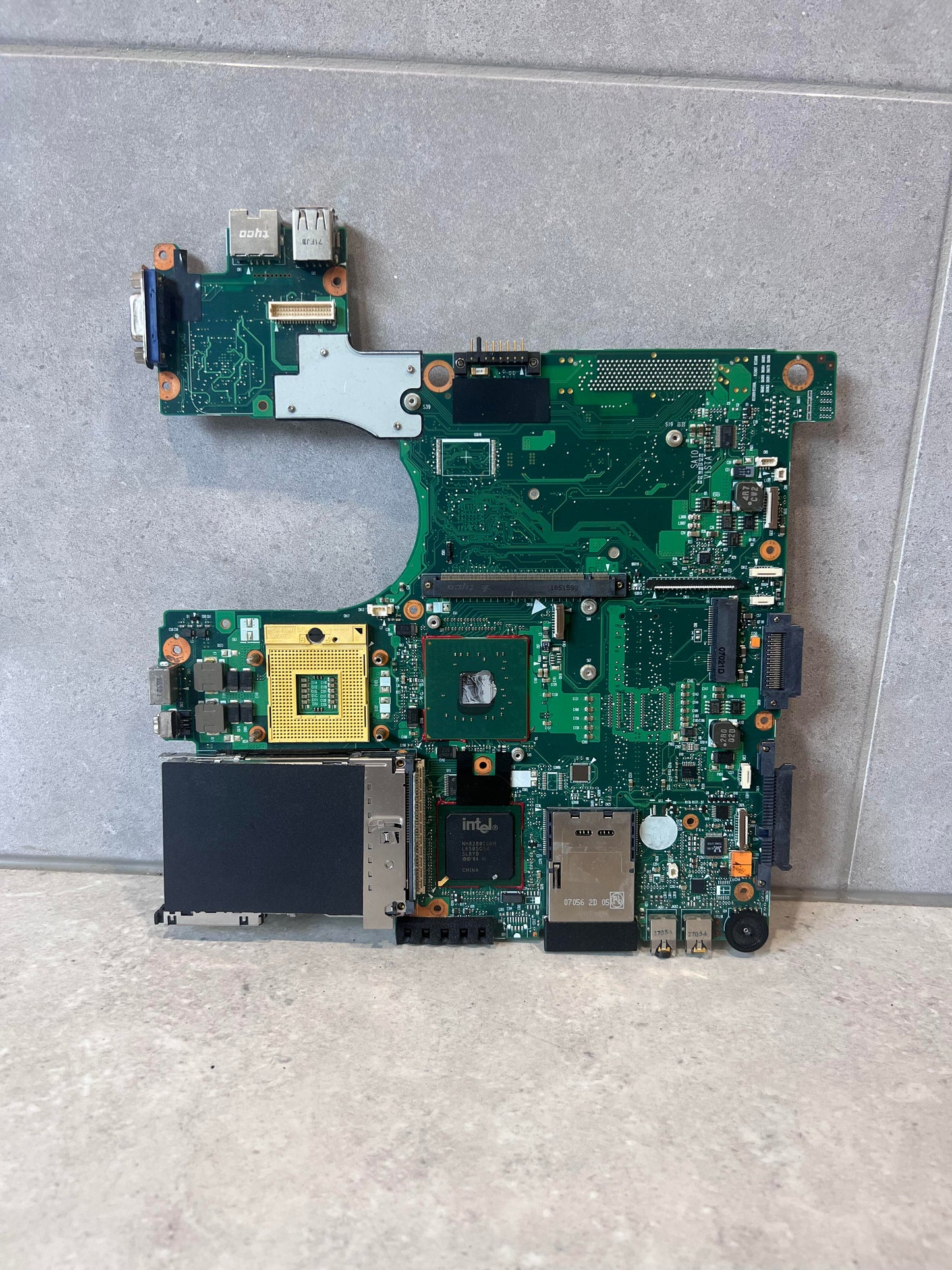Front view of laptop motherboard with exposed ports and Intel chipset