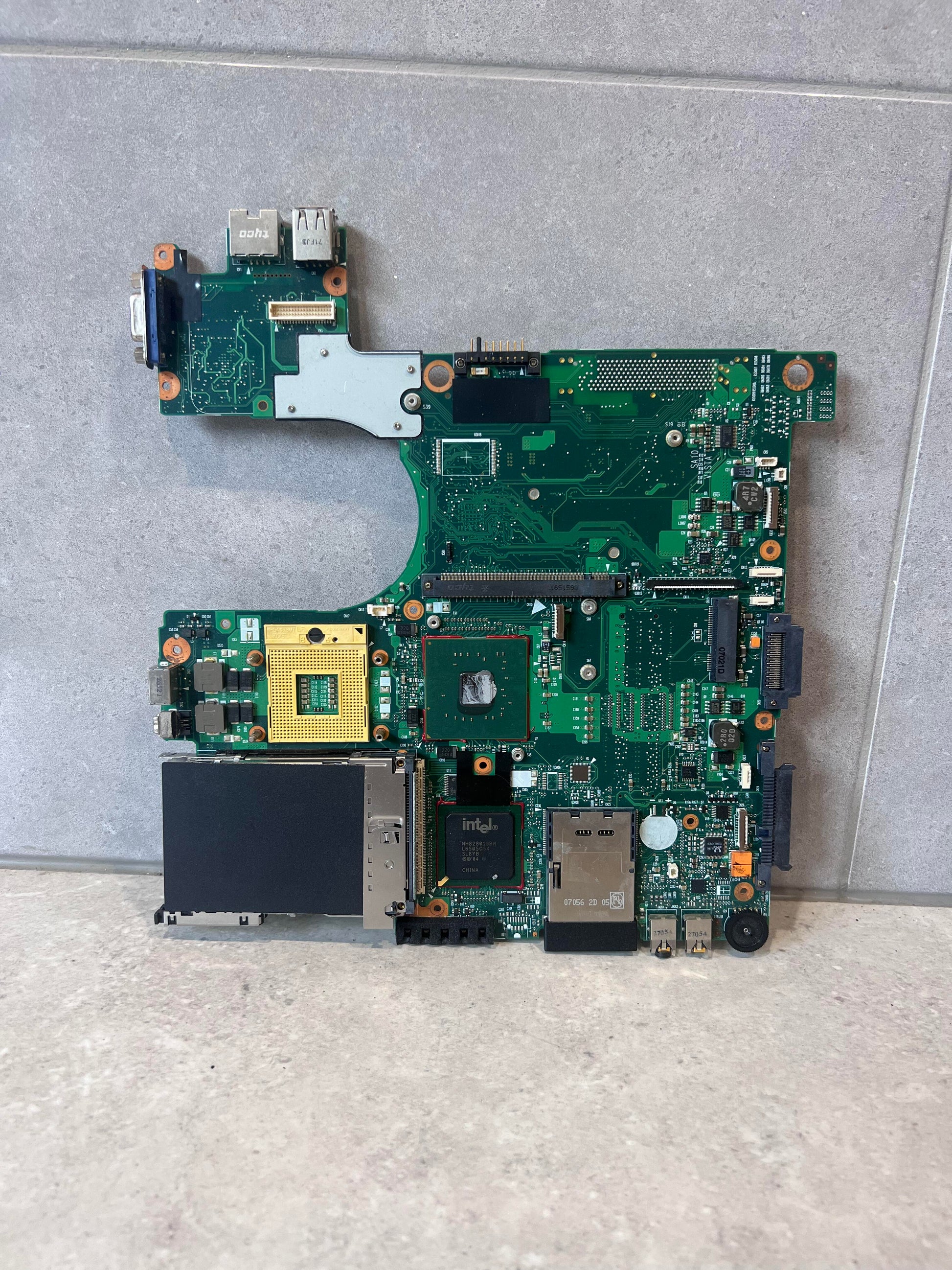 Front view of laptop motherboard with exposed ports and Intel chipset