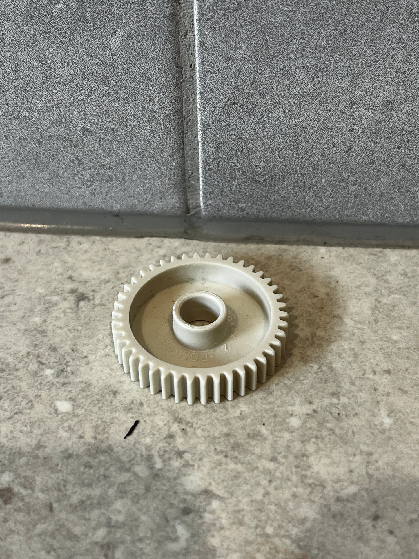 White plastic gear wheel on gray stone surface