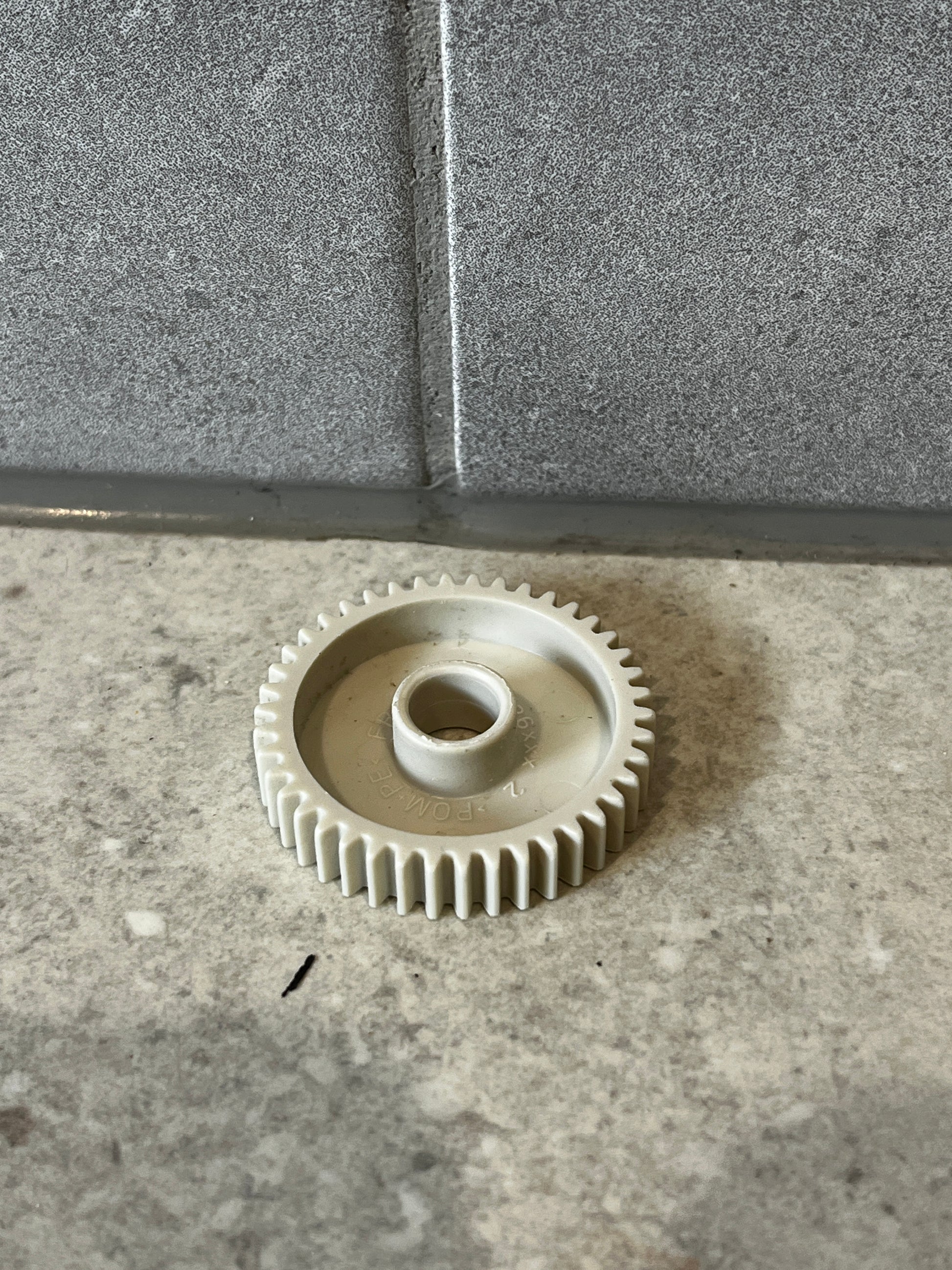 White plastic gear wheel on gray stone surface