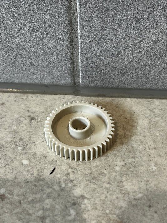 White plastic gear wheel on gray stone surface