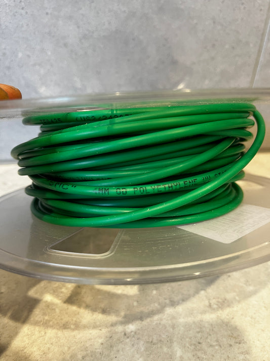 Spool of green polyethylene electrical wire coiled neatly on transparent plastic reel
