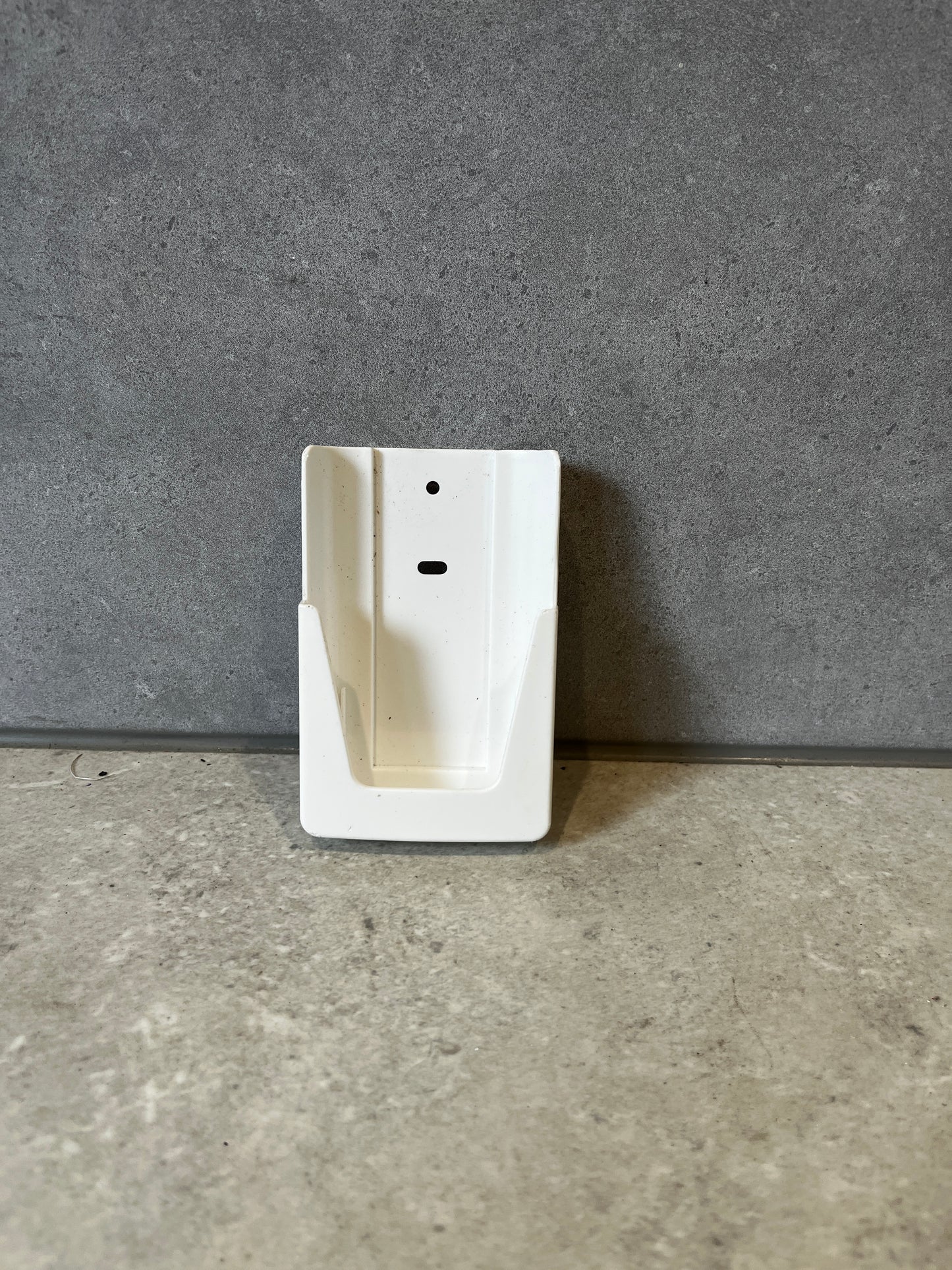 White plastic wall mount bracket on a gray stone surface