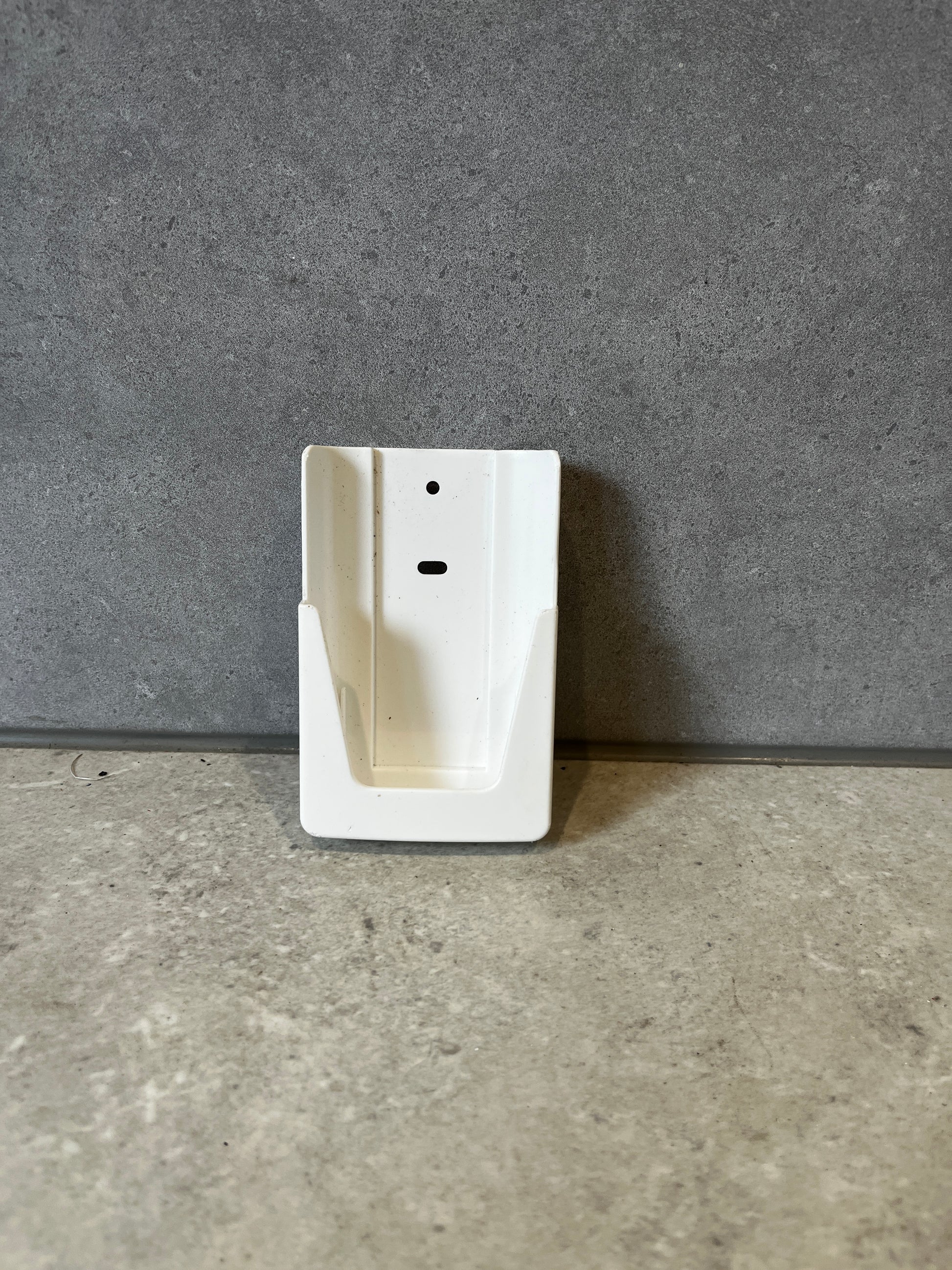 White plastic wall mount bracket on a gray stone surface