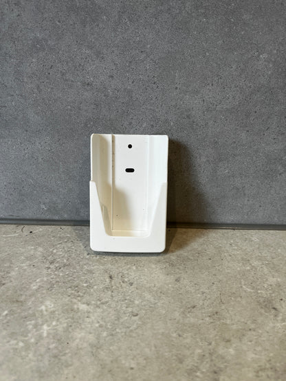 White plastic wall mount bracket on a gray stone surface