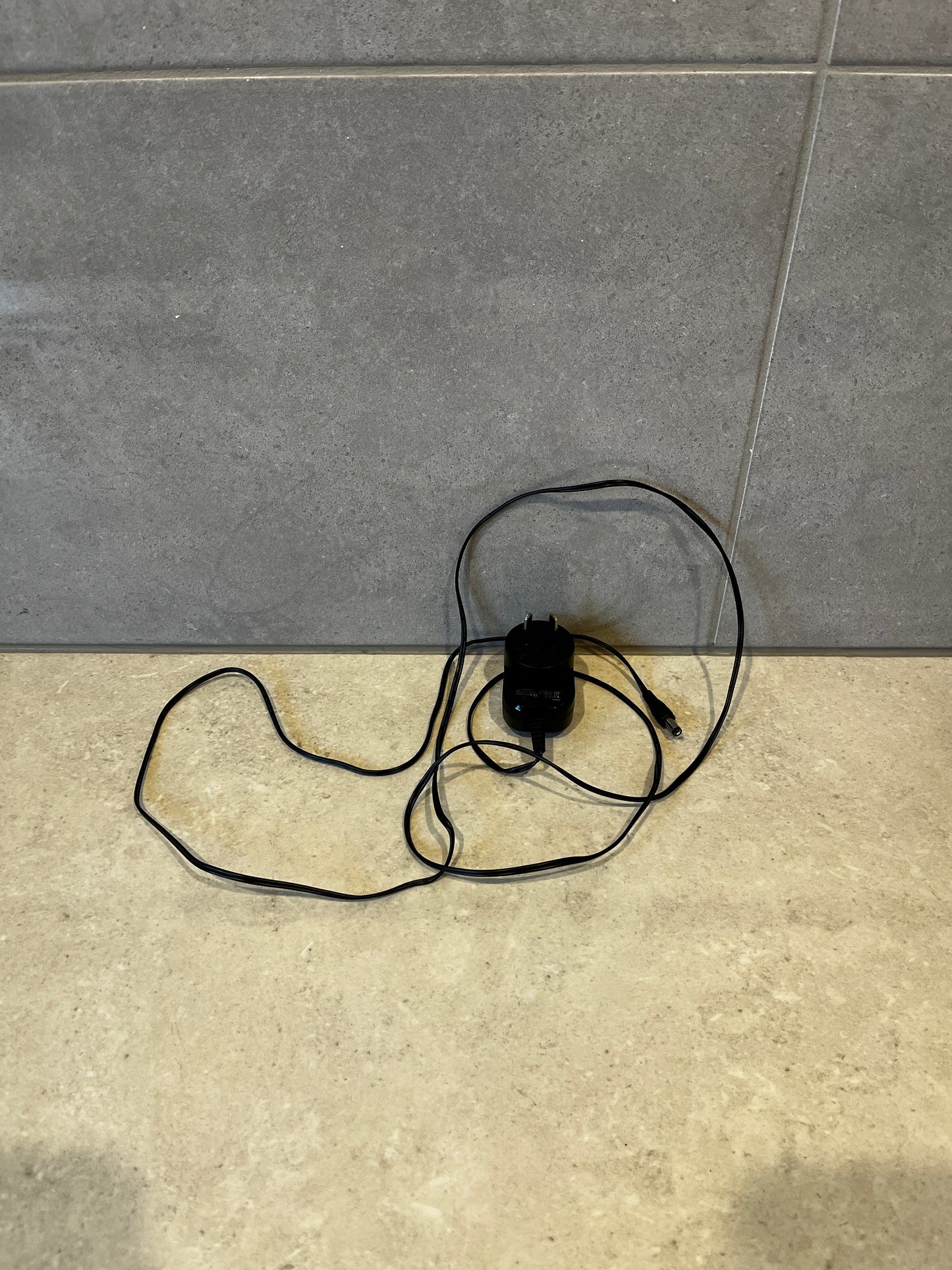 Black 16V 200mA power adapter with long cable on countertop