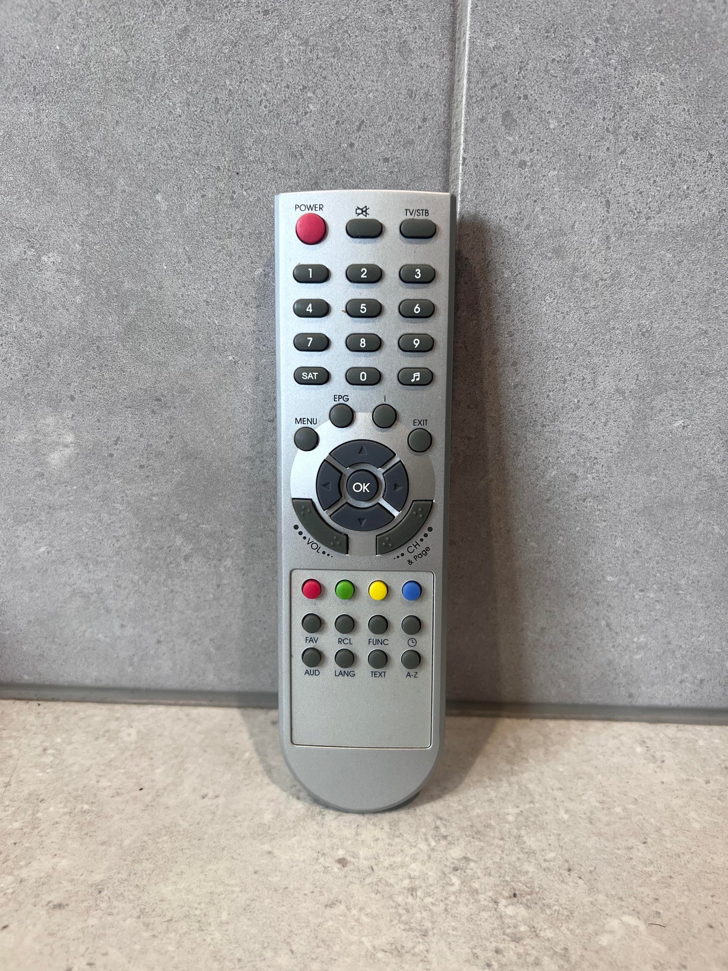 Universal remote control for TV and set-top box standing upright on a light surface