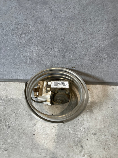 Refrigerator temperature control thermostat with coiled sensor on a gray surface