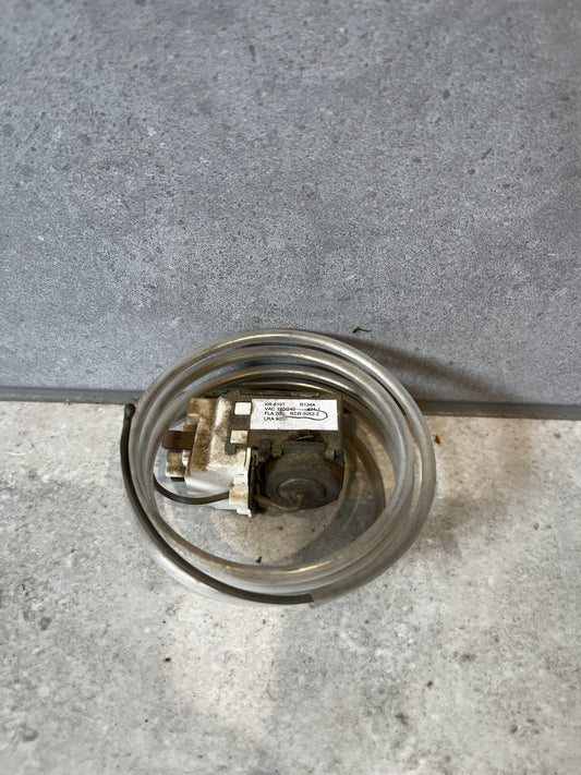 Refrigerator temperature control thermostat with coiled sensor on a gray surface